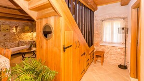 A wooden interior with a stone wall, a wooden bench, a small table, and a plant. - House Bilusic (Jelsa)
