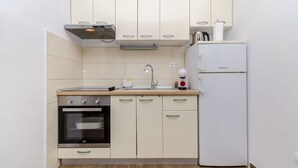 A compact kitchen with a built-in oven, a sink, and a white refrigerator. - Apartments Lida (Jelsa)