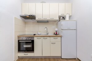 Eine kompakte Küche mit Backofen, Spüle und einem weißen Kühlschrank.