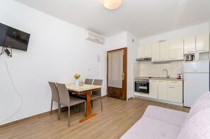 Eine moderne Küche mit Einbauofen, Kühlschrank und Mikrowelle. Ein Essbereich mit Tisch und Stühlen, sowie ein an der Wand befestigter Fernseher.