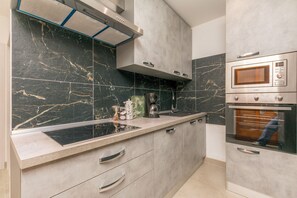A kitchen with a built-in microwave, oven, and gas stove. - Apartment Sealine One (Omis)