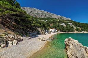 Eine Küstenlandschaft mit klarem Wasser, felsigem Gelände und Gebäuden an einem Hang.