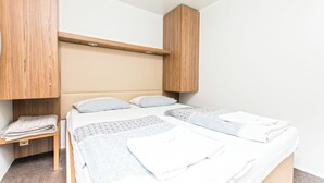 Een slaapkamer met een bed, twee kussens, een nachtkastje en een houten hoofdbord.