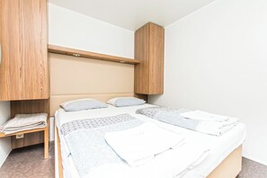 Quarto com cama, duas almofadas, mesa de cabeceira e cabeceira de madeira.