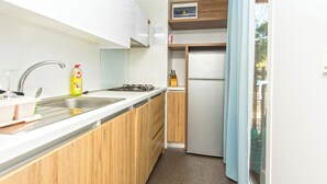 Een kleine keuken met een spoelbak, fornuis en een kleine koelkast.