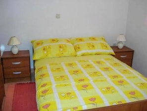 Ein Bett mit gelber Blumenbettwäsche, zwei Nachttische mit Lampen und ein roter Teppich.