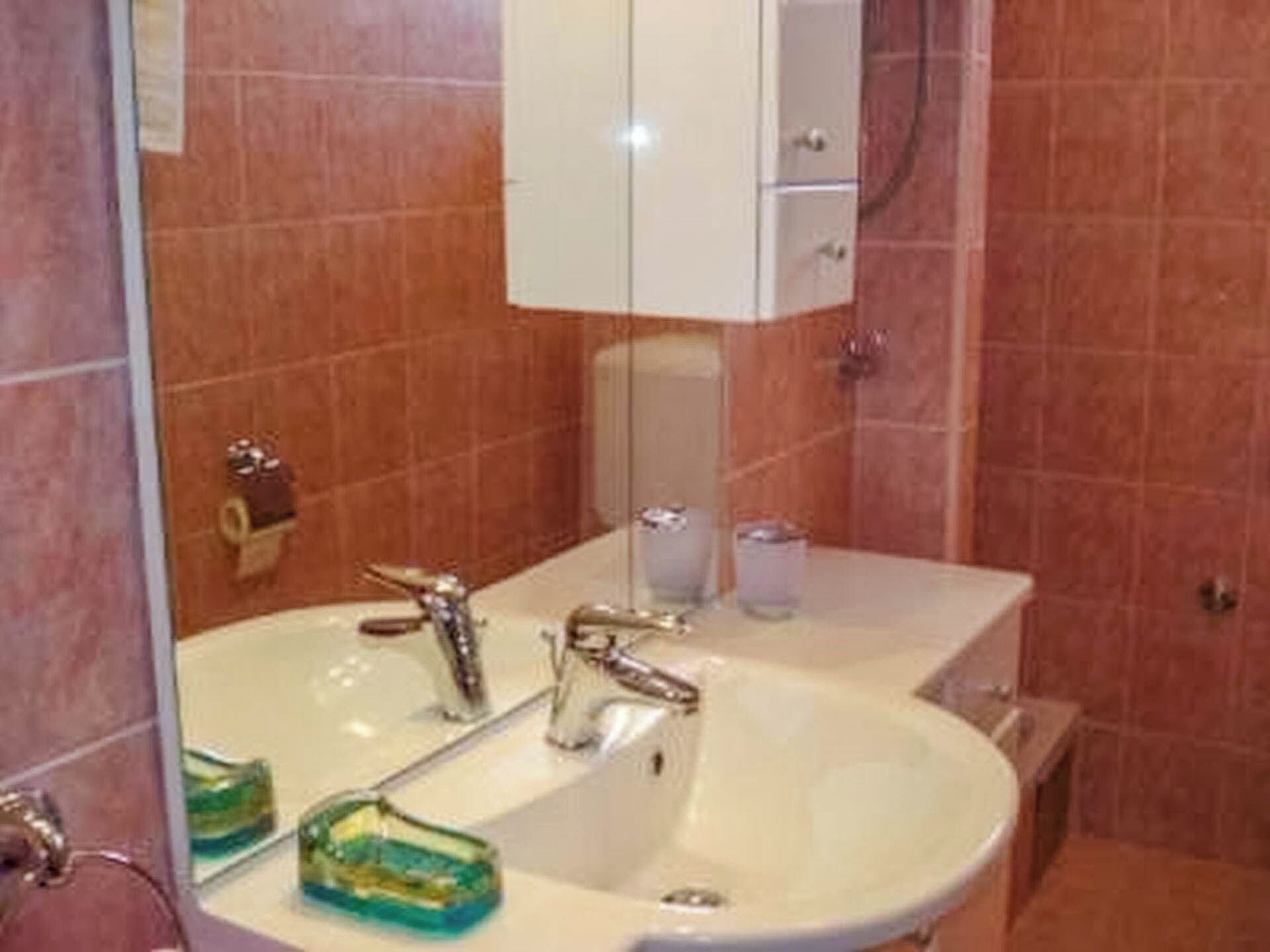 A bathroom with a white sink, a mirror, and a cabinet.