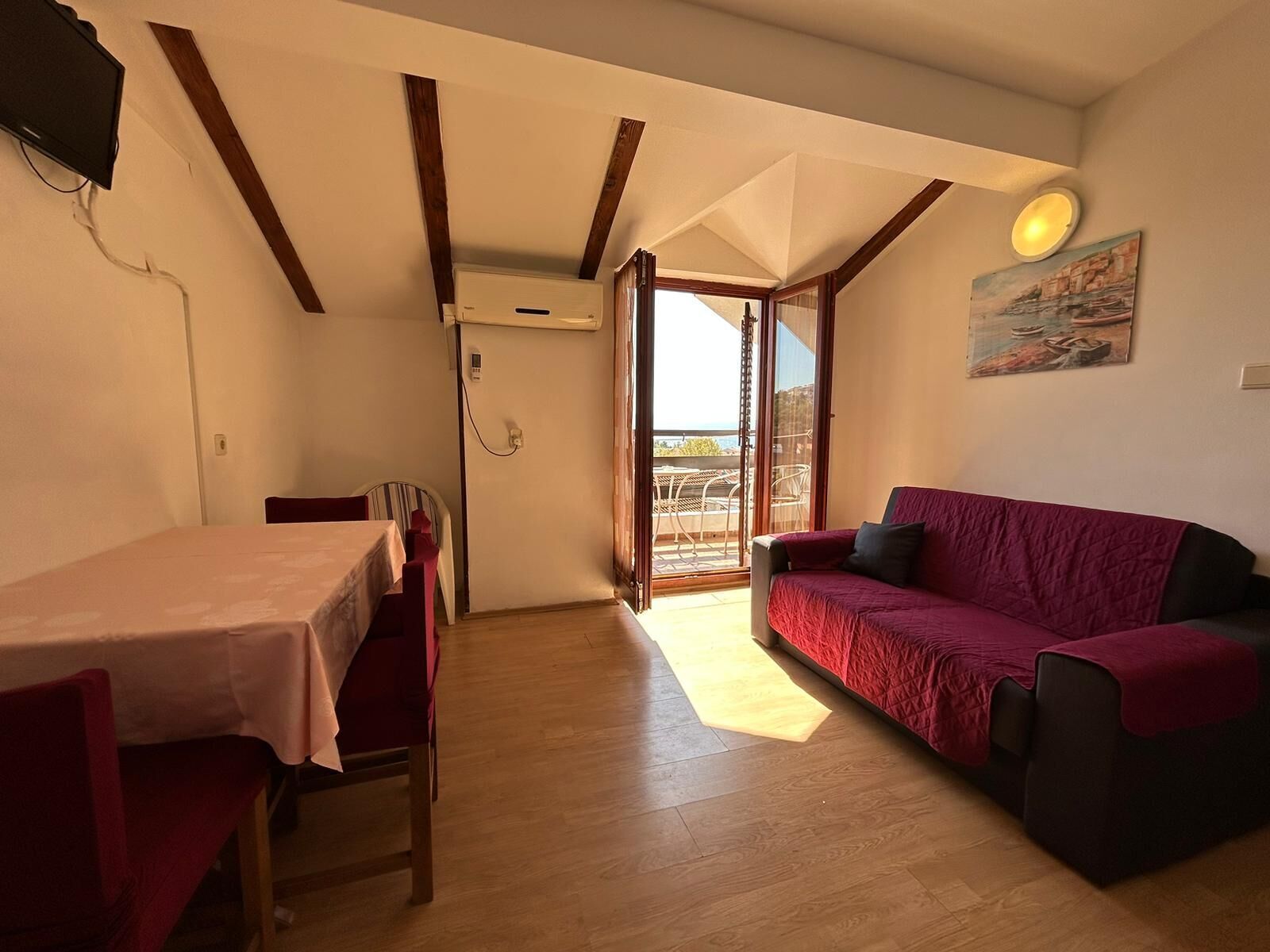 Ein Zimmer mit Esstisch, Stühlen, einer Couch und einem Balkon mit Blick.