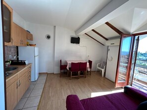 Ein kompakter Wohnraum mit Küchenzeile, Essbereich und einem Balkon mit Blick.