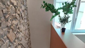 A staircase with a stone wall on one side and a wooden railing on the other, leading to a bright interior space.