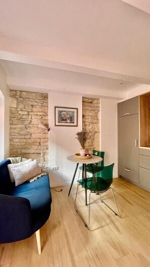 Una habitación con pared de piedra, una mesa de comedor con sillas, un sofá y un armario.
