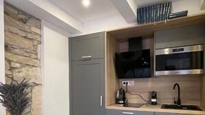 A modern kitchen with grey cabinets, a built-in oven, and a round dining table with a glass chair.