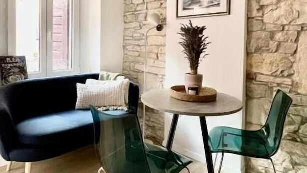A modern living room with a stone wall, a round table with chairs, a sofa, and a potted plant.