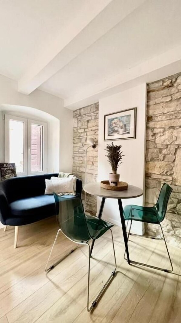 Un salon moderne avec un mur en pierre, une table ronde entourée de chaises, un canapé et une plante en pot.