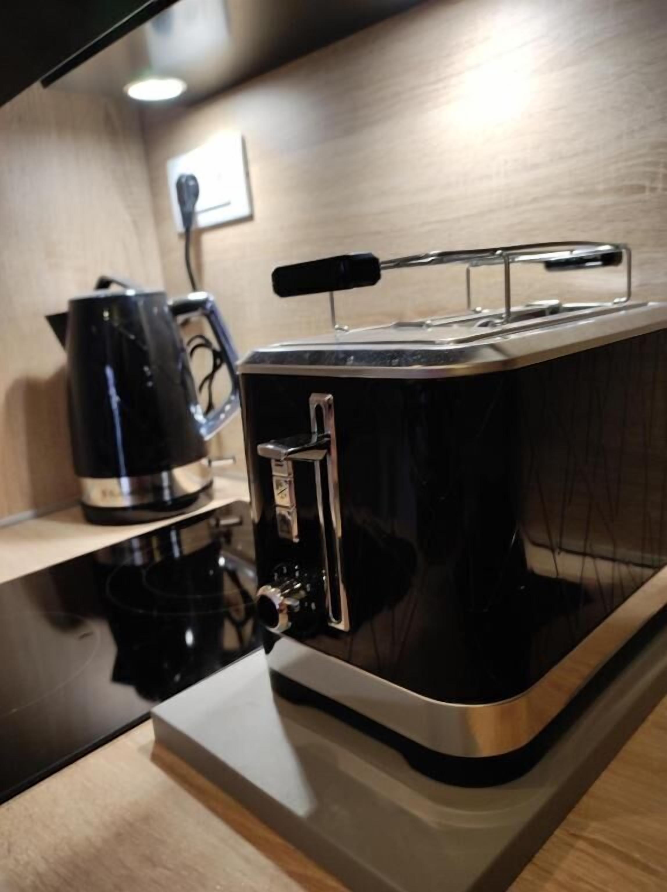 Een keuken met een zwarte broodrooster en een zwarte koffiezetapparaat op het aanrecht.