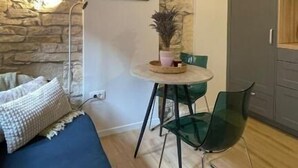 A room with a stone wall, a bed, a table with chairs, and a door.
