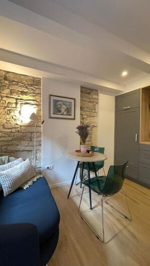 Une pièce avec un mur en pierre, un lit, une table avec des chaises et une porte.