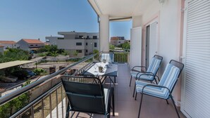 Ein Balkon mit Tisch, Stühlen und einem geparkten Auto vor dem Haus.