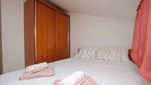 Ein Hotelzimmer mit einem Bett, einem Holzschrank und einem rosa Vorhang.