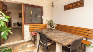 Eine mit Steinplatten ausgelegte Terrasse mit einer Holzbank, einem Tisch und Stühlen.