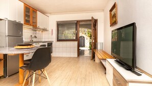 Eine kompakte Küche mit Essbereich, Fernseher und Blick ins Freie.