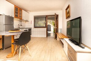 A compact kitchen with a dining area, a TV, and a view to the outside. - Apartment Maria Stay (Okrug)
