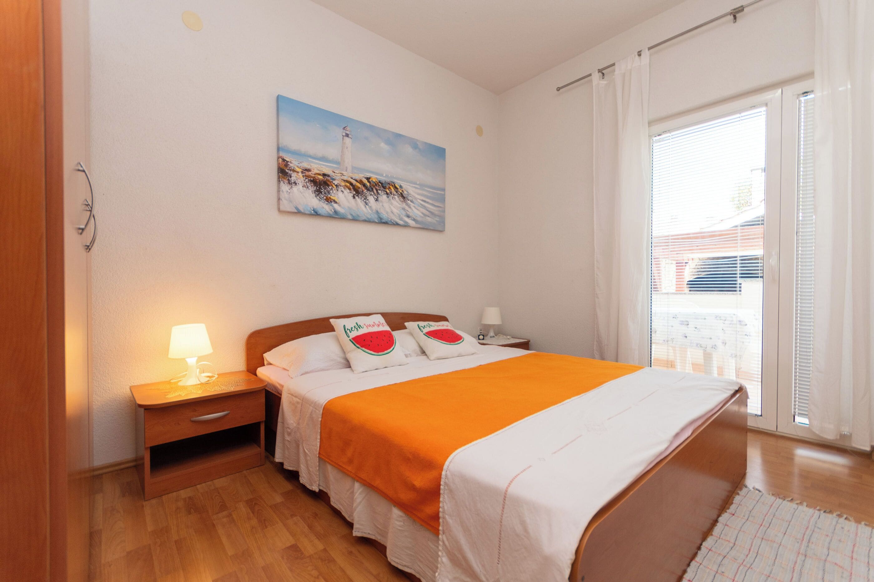 Ein Schlafzimmer mit Bett, Nachttisch, Lampe und einem Gemälde an der Wand.