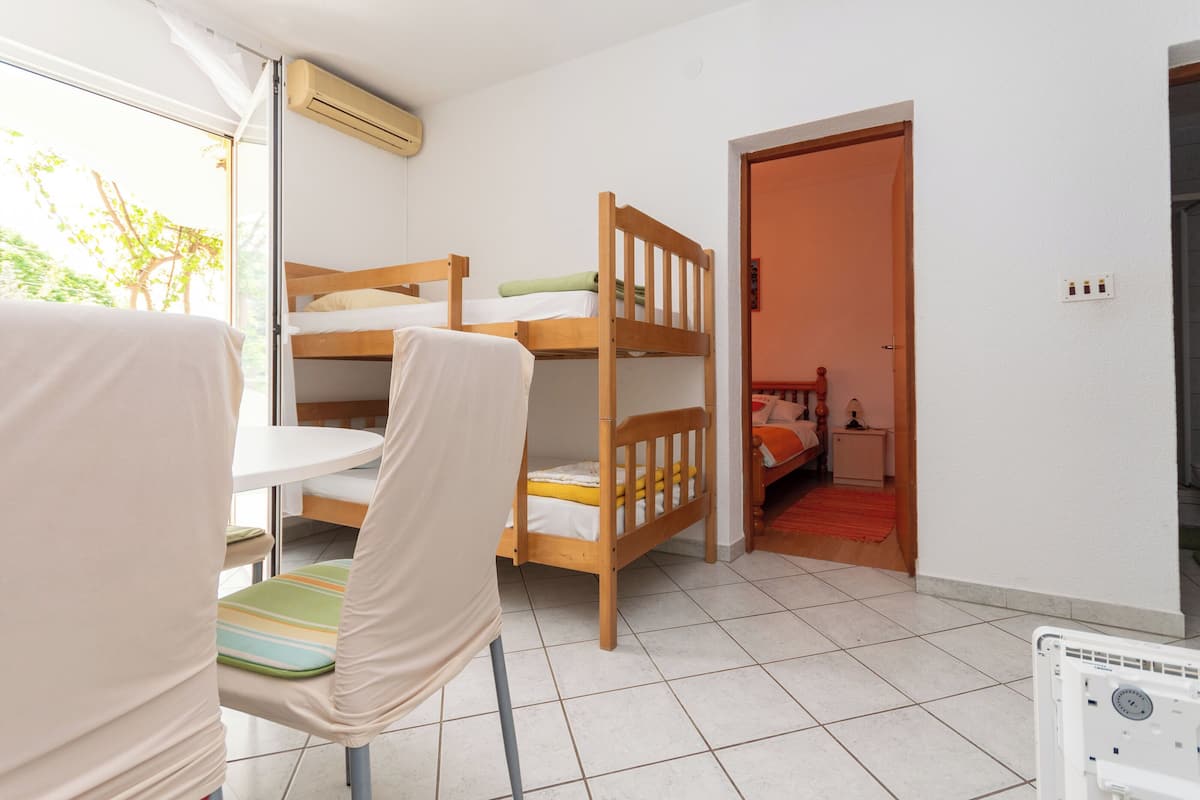 Una habitación con literas, una mesita, una silla y un radiador.