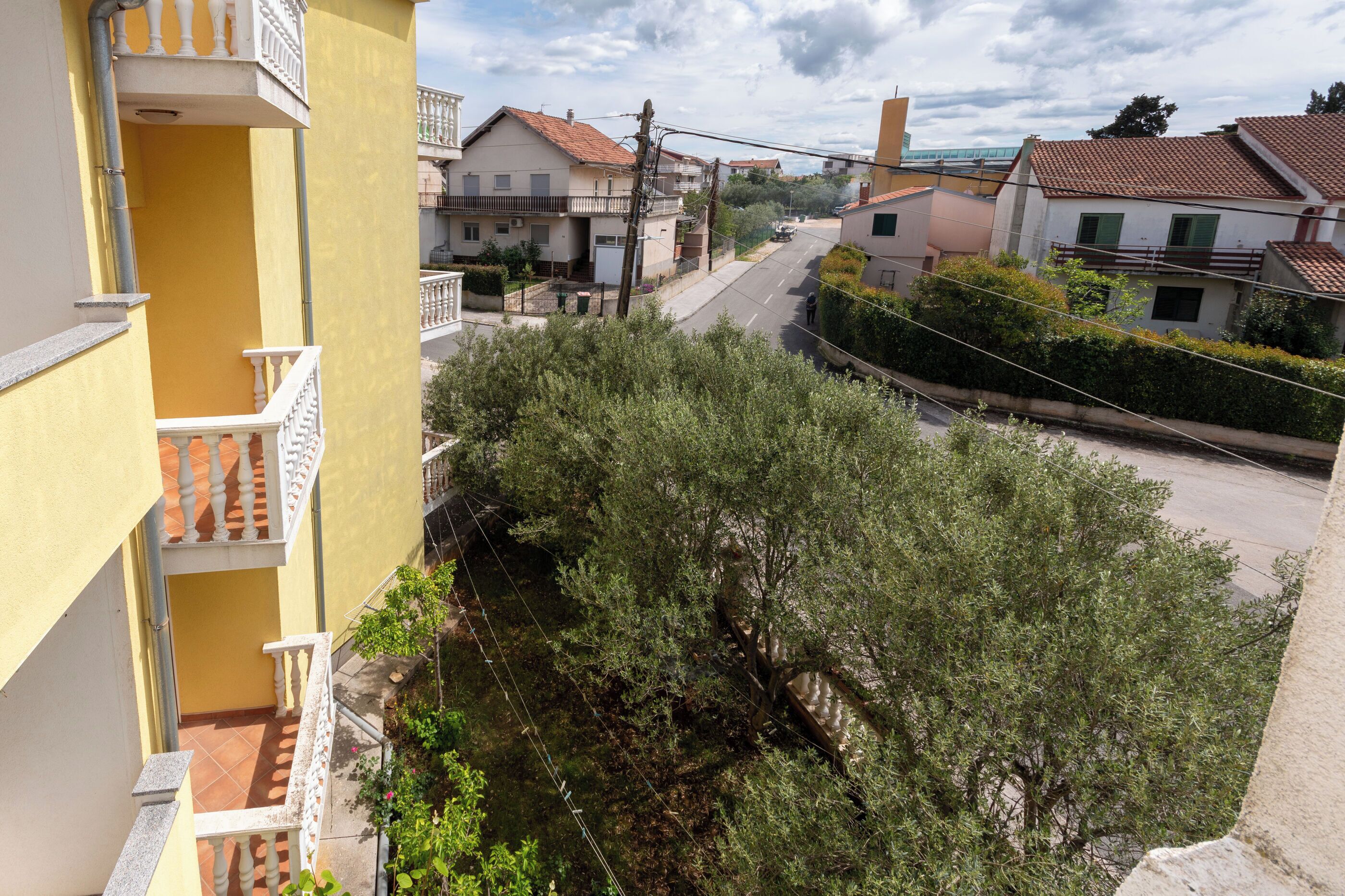 Une rue résidentielle bordée de maisons, un immeuble jaune doté de balcons et des arbres.