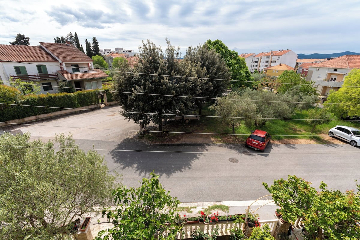 Una calle residencial con casas, un árbol y coches estacionados.