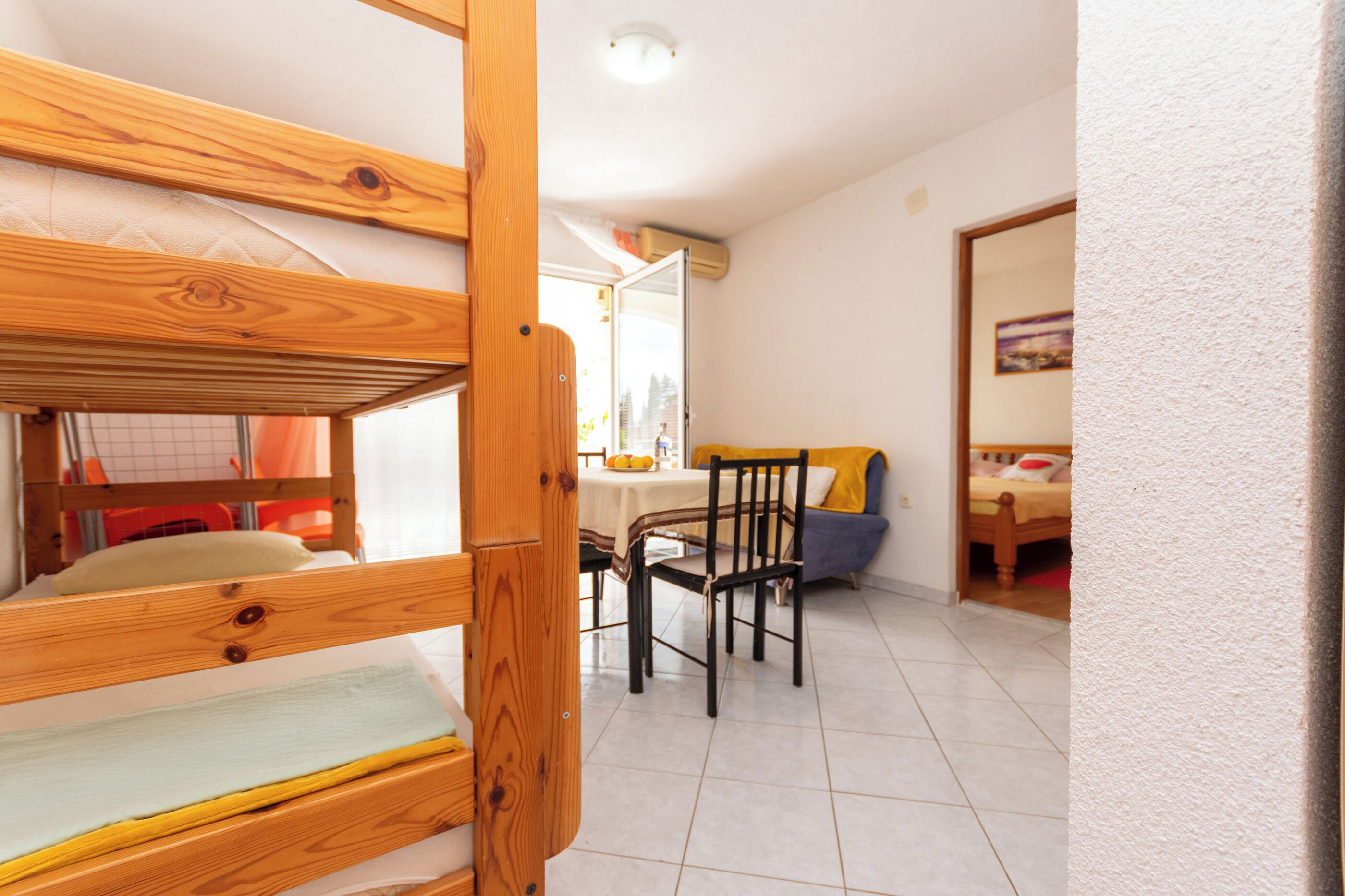 Une chambre avec un lit superposé, une table à manger avec des chaises et un canapé.