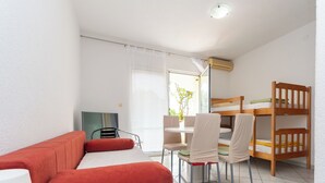 A compact room with a red sofa, a small table, a bunk bed, and a TV.