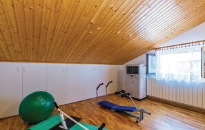 Ein Zimmer mit Holzboden, Trainingsgeräten, einem grünen Übungsball und einem Fenster mit Vorhängen.