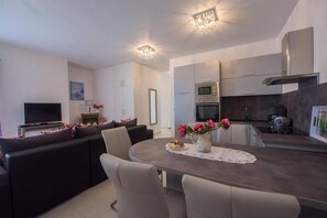 A modern living room with a sofa, TV, and a dining area with a table and chairs. - Apartments Guliana Tisno (Tisno)