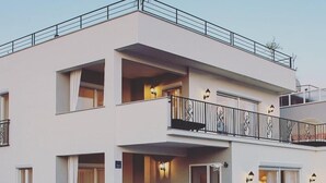 A two-story building with balconies, a staircase, and exterior lighting.