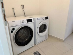 A Hisense washing machine and dryer in a laundry room with a tiled floor and a white wall. - Apartments Guliana Tisno (Tisno)