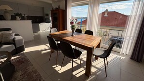 A modern living room with a dining table, chairs, a sofa, and a view of the outside.