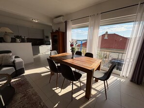 A modern living room with a dining table, chairs, a sofa, and a view of the outside.