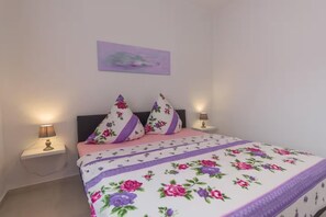 Ein Schlafzimmer mit einem Bett, zwei Kissen, einem Nachttisch mit Lampe und einem Wandbild.
