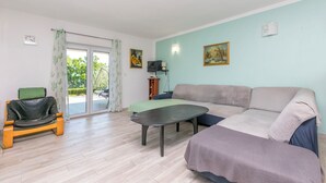 A living room with a sofa, a coffee table, a chair, a television, and a painting on the wall. - Apartment Perfect (Omis)