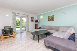 A living room with a sofa, a coffee table, a chair, a television, and a painting on the wall. - Apartment Perfect (Omis)