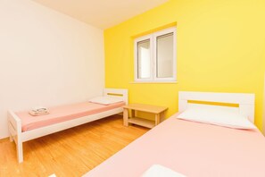 Ein Zimmer mit zwei Betten, einem Fenster und einem kleinen Holztisch.