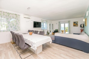 Ein modernes Wohnzimmer mit Essbereich, einem Flachbildfernseher und einer Couch.