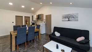 Un espacio habitable moderno con comedor, cocina y un sofá negro con almohada blanca.