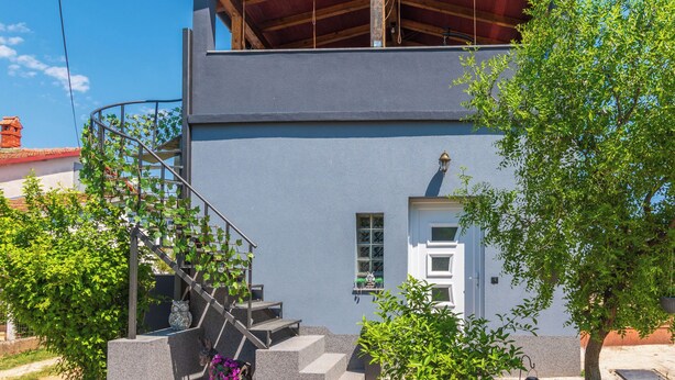 Un edificio de dos pisos con una escalera que lleva a un nivel superior, una ventana pequeña y una puerta.