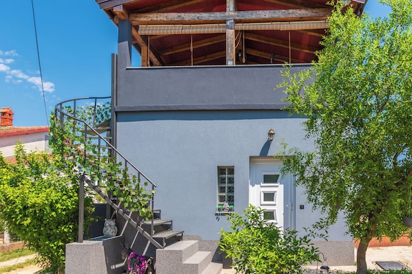 A two-story building with a staircase leading to an upper floor, a small window, and a door. - Apartment Ruben (Liznjan)