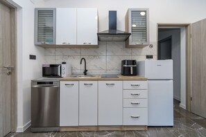 A modern kitchen with a dishwasher, microwave, coffee maker, and refrigerator.