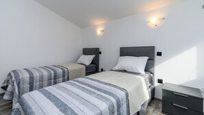 Un dormitorio con dos camas, una mesita de noche y luces fijadas a la pared.
