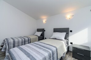 A bedroom with two beds, a nightstand, and wall-mounted lights. - Apartment Ruben (Liznjan)
