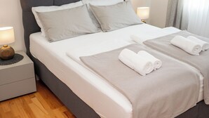 Ein ordentlich bezogenes Bett mit Kissen und Handtüchern, eine Nachttischlampe und ein Nachttisch.